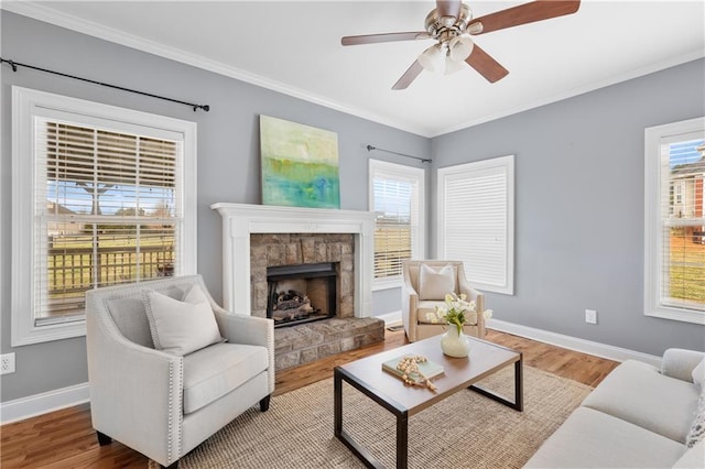 living area featuring ornamental molding, a ceiling fan, baseboards, and wood finished floors