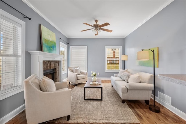 living area featuring a ceiling fan, wood finished floors, baseboards, and ornamental molding