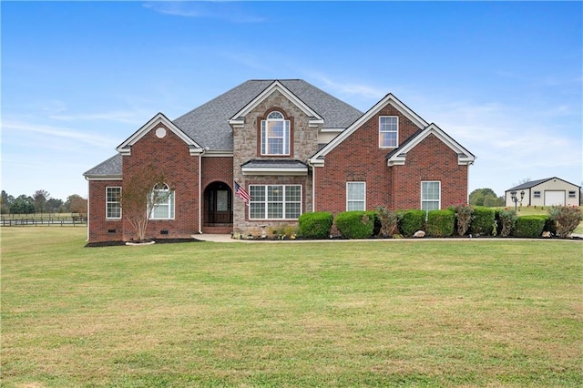 traditional home featuring brick siding, crawl space, a front yard, and roof with shingles