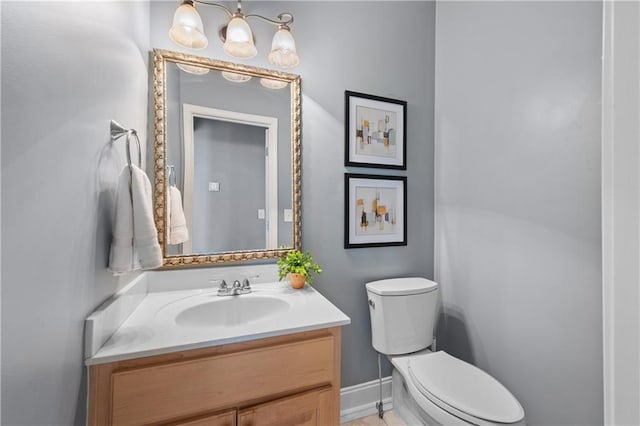 bathroom with baseboards, toilet, and vanity