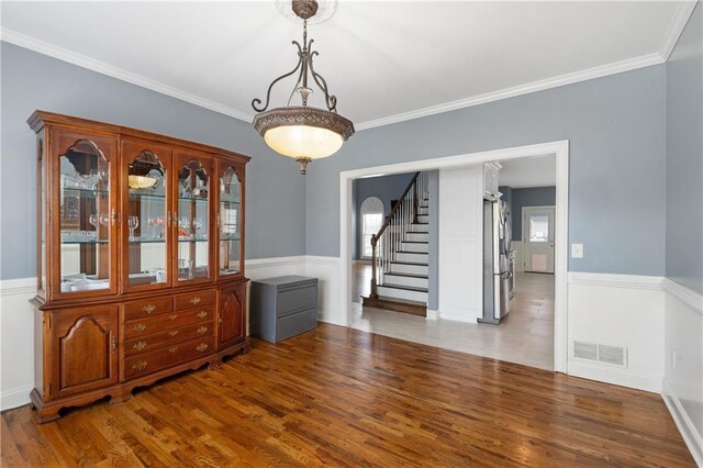 unfurnished dining area with stairs, crown molding, wood finished floors, and visible vents