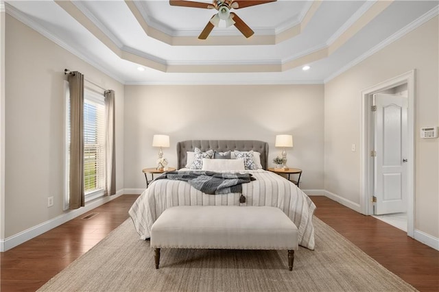 bedroom featuring baseboards, a tray ceiling, ornamental molding, wood finished floors, and a ceiling fan