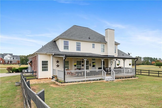 rear view of house featuring ceiling fan, fence, a porch, a chimney, and a yard