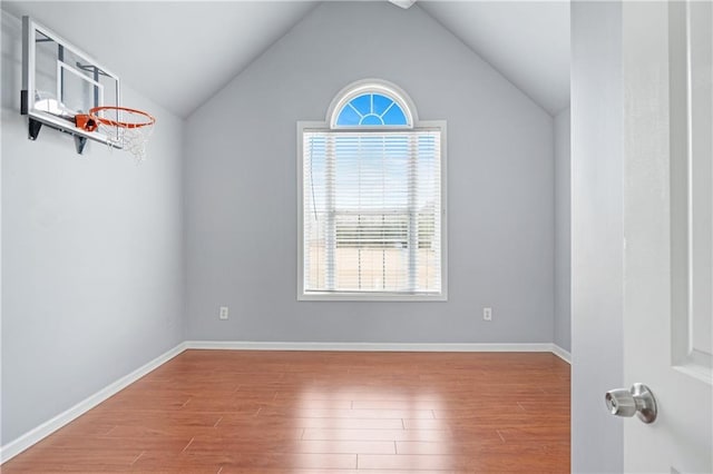 empty room with lofted ceiling, wood finished floors, and baseboards