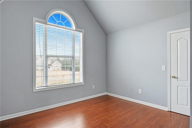 unfurnished room featuring baseboards, dark wood finished floors, and vaulted ceiling