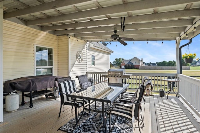 wooden deck featuring outdoor dining area, a ceiling fan, and grilling area