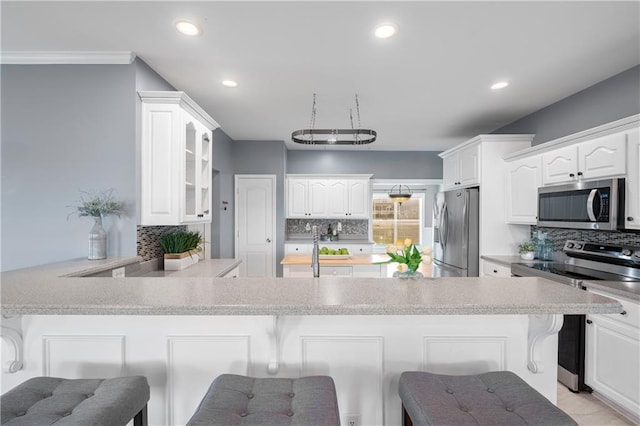 kitchen with glass insert cabinets, a breakfast bar, decorative backsplash, a peninsula, and stainless steel appliances