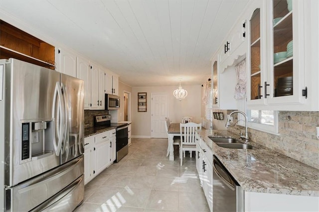 kitchen featuring light tile patterned floors, decorative backsplash, an inviting chandelier, appliances with stainless steel finishes, and a sink