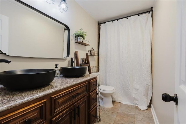 full bath with double vanity, a shower with shower curtain, toilet, a sink, and baseboards