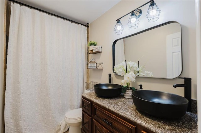 full bathroom featuring double vanity, a sink, and toilet