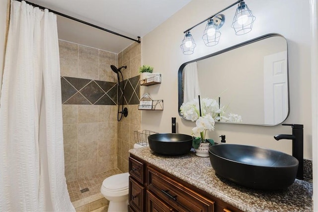 full bath featuring toilet, tiled shower, and vanity