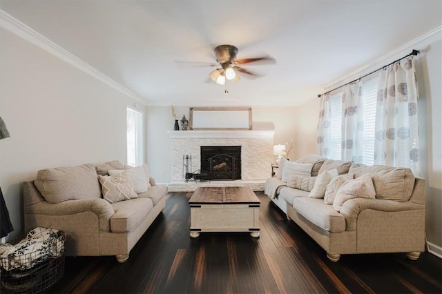 living area with dark wood-style flooring, a fireplace, a ceiling fan, and crown molding