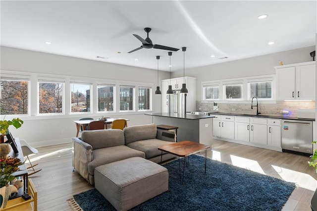 living room with ceiling fan, sink, and light hardwood / wood-style floors