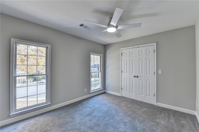 unfurnished bedroom featuring ceiling fan, a closet, carpet floors, and multiple windows