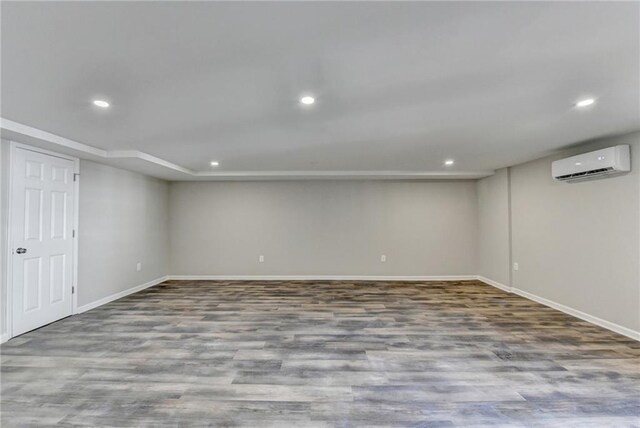 basement featuring a wall mounted air conditioner and hardwood / wood-style floors