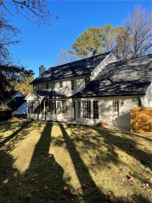 rear view of property with a sunroom and a yard