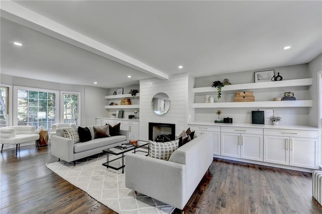 living room with beamed ceiling, wood-type flooring, and a large fireplace