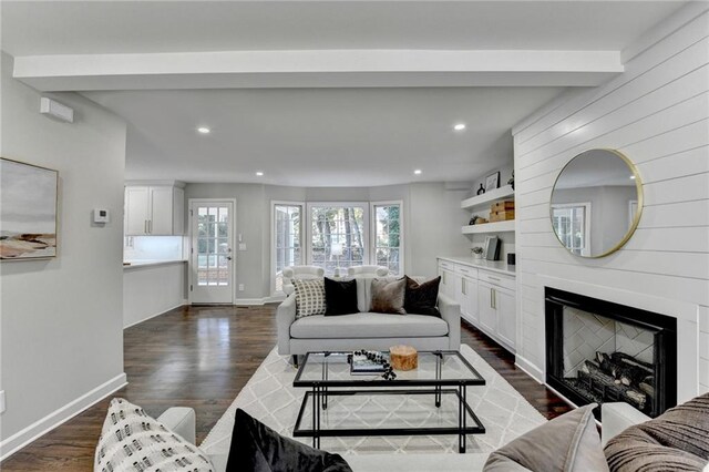 living room featuring beam ceiling, dark hardwood / wood-style flooring, and a fireplace