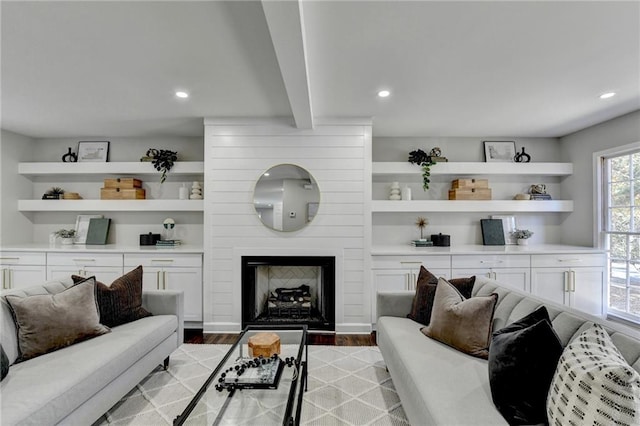 living room featuring beam ceiling, a large fireplace, and light hardwood / wood-style floors