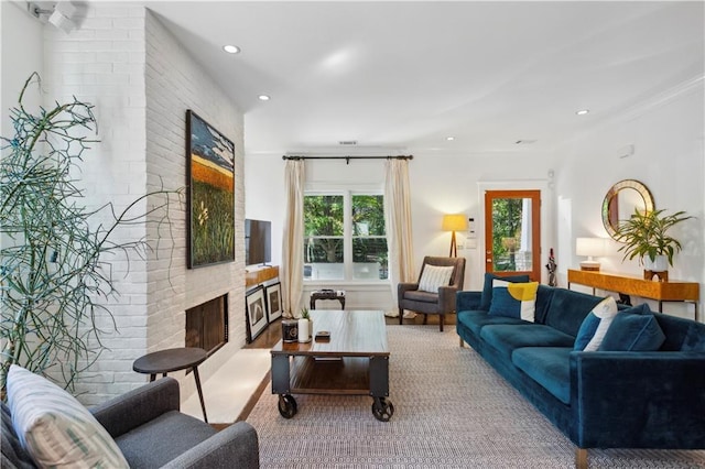 living room with a brick fireplace and ornamental molding