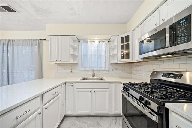 kitchen with visible vents, stainless steel appliances, white cabinetry, open shelves, and a sink