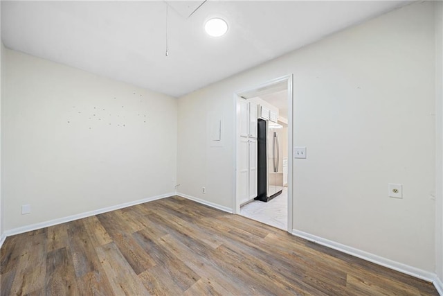 spare room with attic access, baseboards, and wood finished floors