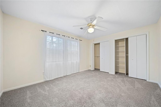 unfurnished bedroom featuring carpet floors, two closets, a ceiling fan, and baseboards