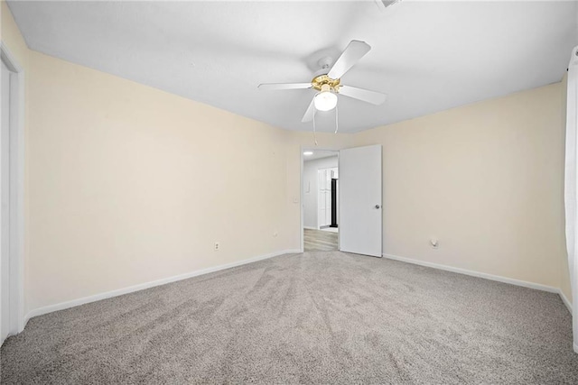 carpeted empty room featuring ceiling fan and baseboards