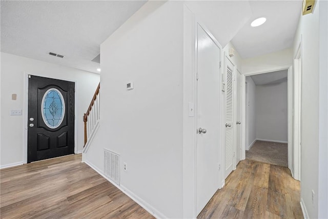 entrance foyer featuring stairs, visible vents, and wood finished floors