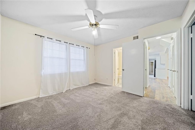 carpeted spare room with ceiling fan, visible vents, and baseboards