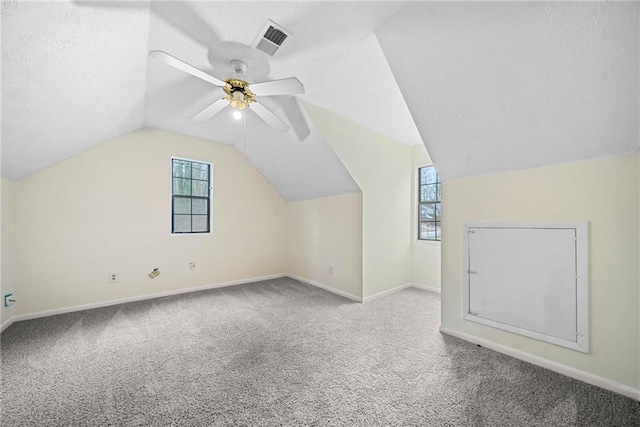 additional living space with a textured ceiling, carpet floors, visible vents, and a healthy amount of sunlight