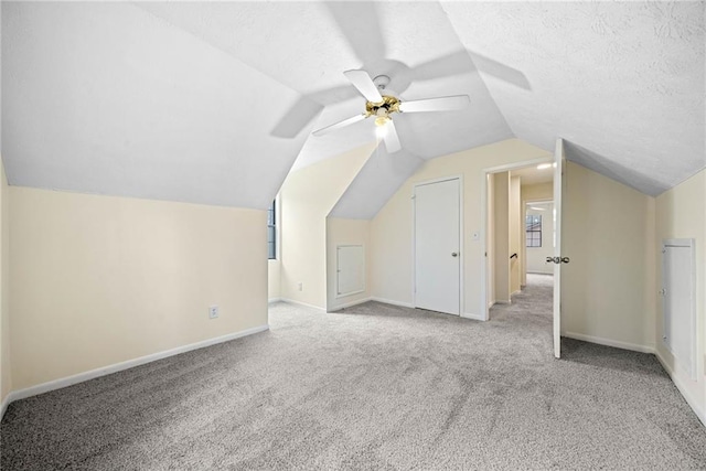 additional living space featuring lofted ceiling, carpet, baseboards, and a textured ceiling