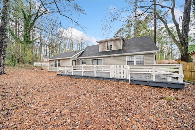 rear view of house with fence and a deck