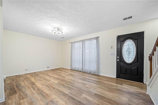 entrance foyer featuring baseboards, visible vents, stairway, wood finished floors, and a textured ceiling