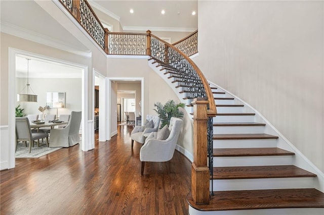 staircase with crown molding, recessed lighting, a towering ceiling, wood finished floors, and baseboards