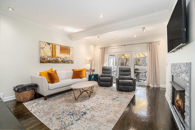 living area with a warm lit fireplace, wood-type flooring, baseboards, and crown molding