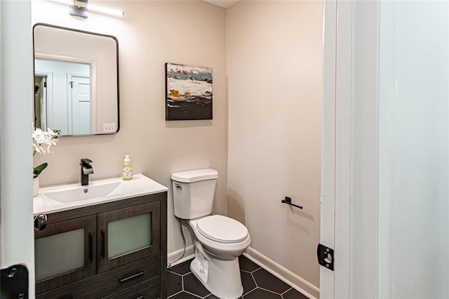 half bath with baseboards, vanity, toilet, and tile patterned floors