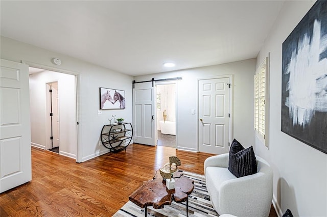 living area featuring a barn door, wood finished floors, and baseboards