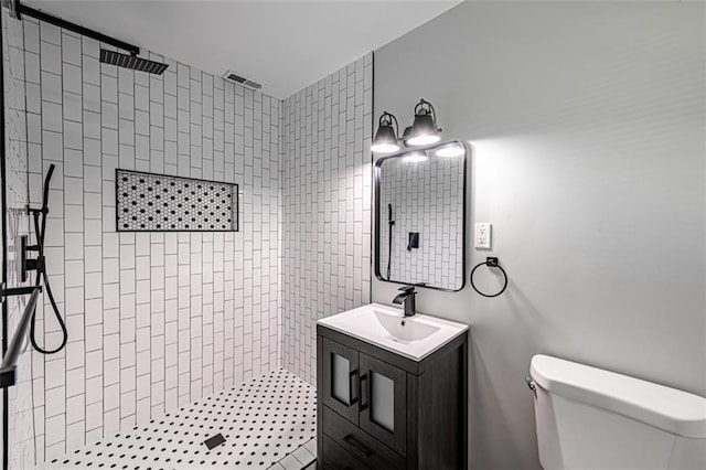 full bath with toilet, tiled shower, and vanity