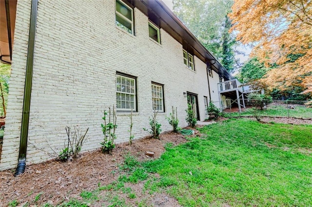 view of home's exterior featuring brick siding, fence, and a lawn