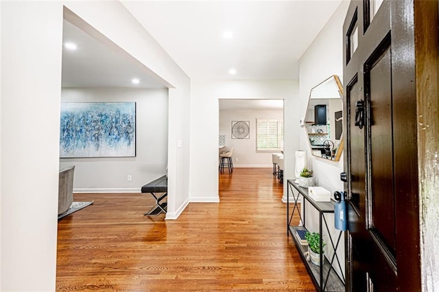 corridor with baseboards, wood finished floors, and recessed lighting