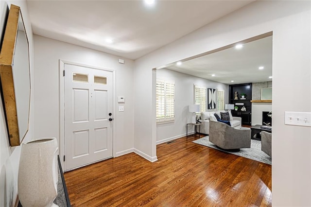 foyer entrance featuring recessed lighting, a fireplace, baseboards, and wood finished floors