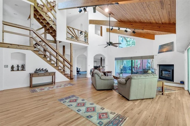 living room with high vaulted ceiling, light hardwood / wood-style flooring, ceiling fan, wooden ceiling, and beam ceiling