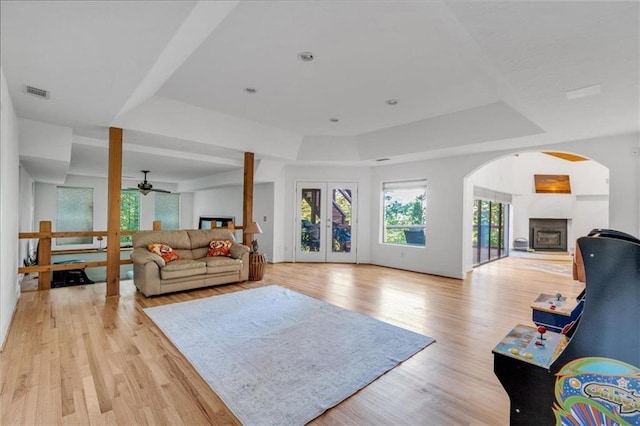 living room with ceiling fan, a tray ceiling, and light hardwood / wood-style floors