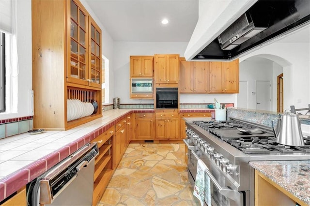 kitchen featuring appliances with stainless steel finishes, tile counters, and extractor fan