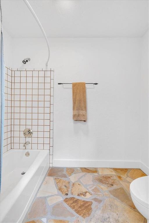 bathroom featuring toilet and tiled shower / bath