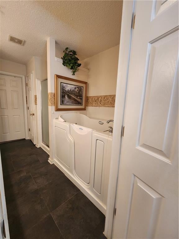 corridor with dark tile patterned floors and a textured ceiling