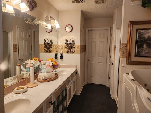 bathroom with a bathing tub, vanity, a textured ceiling, and tile patterned floors