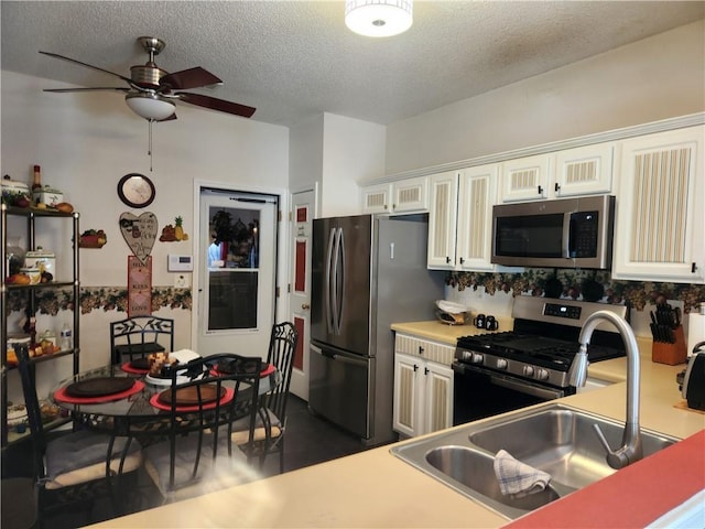 kitchen featuring appliances with stainless steel finishes, a textured ceiling, ceiling fan, sink, and white cabinetry