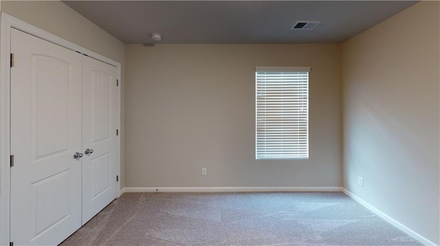 unfurnished bedroom featuring carpet flooring, baseboards, visible vents, and a closet